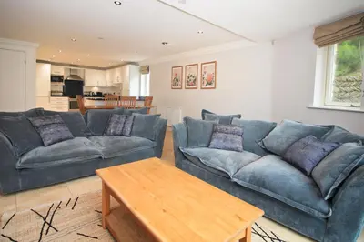a living room with two blue couches and a table at BEACHSIDE SPACIOUS apartment, private garden in St Merryn