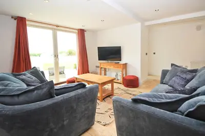 a living room with two couches and a television at BEACHSIDE SPACIOUS apartment, private garden in St Merryn