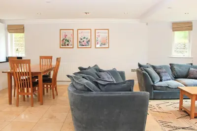 a living room with a couch and a table at BEACHSIDE SPACIOUS apartment, private garden in St Merryn