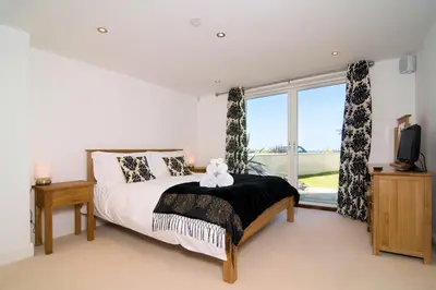 a bedroom with a bed with a teddy bear on it at BY THE BEACH, spacious apartment in St Merryn