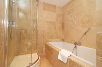 a bathroom with a shower and a tub and a sink at BY THE BEACH, spacious apartment in St Merryn