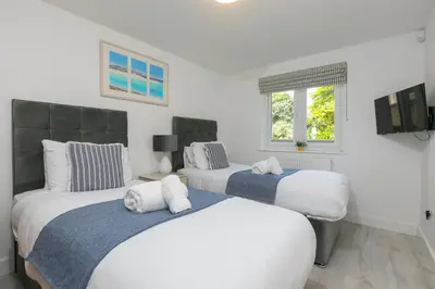 two beds in a bedroom with white walls at Lamorna in St Ives