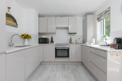 a white kitchen with white cabinets and appliances at Lamorna in St Ives