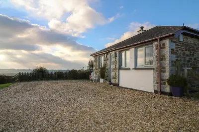 a stone house with a garage on a gravel driveway at Valley View in St Austell