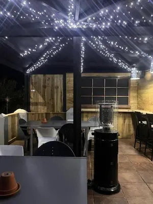 a patio with lights on a tent with tables and chairs at The Thirsty Scholar in Penryn