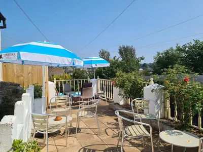 a patio with chairs and tables and an umbrella at The Thirsty Scholar in Penryn