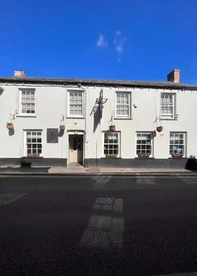 a white building on the side of a street at The Thirsty Scholar in Penryn