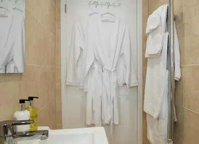 a white robe hanging on a rack in a bathroom at Hillside Studio in Penzance