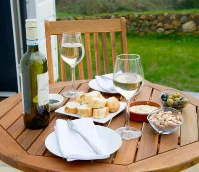 a wooden table with glasses of wine and food on it at Hillside Studio in Penzance
