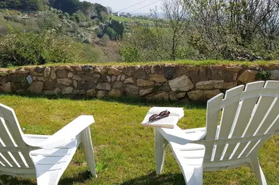 two white chairs and a table in the grass at Hillside Studio in Penzance