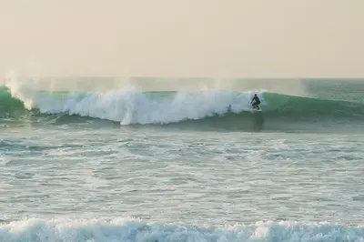 a person riding a wave on a surfboard in the ocean at Hillside Studio in Penzance