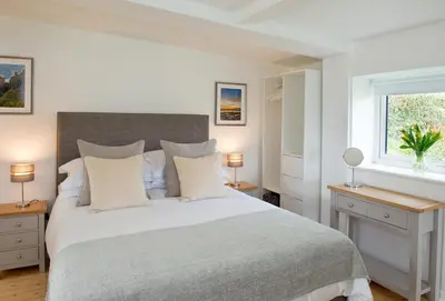 a white bedroom with a large bed with white pillows at Hillside Studio in Penzance