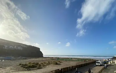 a view of a beach with people walking on the sand at Sunsets In Porthtowan, Beachfront apartment in Porthtowan