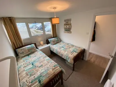 a bedroom with two beds and a window at Sunsets In Porthtowan, Beachfront apartment in Porthtowan