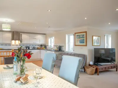 a kitchen and living room with a table and chairs at The White House in Poundstock