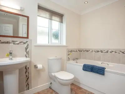a white bathroom with a toilet and a sink at The White House in Poundstock
