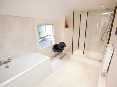 a bathroom with a shower tub and a black chair at 21 British Road in St. Agnes