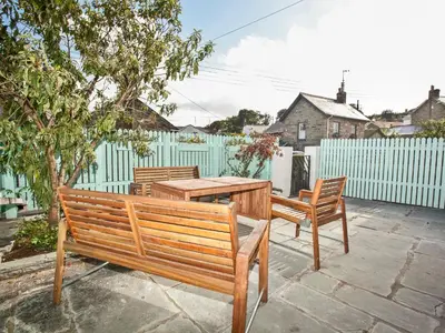 a wooden bench and a table and a fence at 21 British Road in St. Agnes