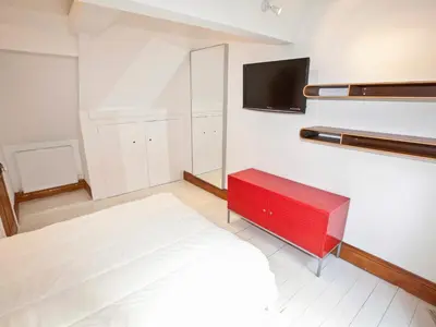 a bedroom with a large bed and a red bench at 21 British Road in St. Agnes