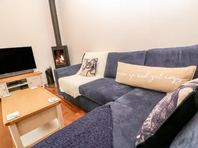 a living room with a blue couch and a tv at Nana's Cottage in Camborne