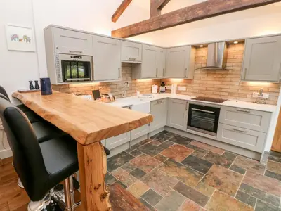 a kitchen with white cabinets and a wooden table at Nana's Cottage in Camborne