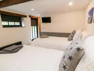 a bedroom with two beds and a tv on the wall at Nana's Cottage in Camborne