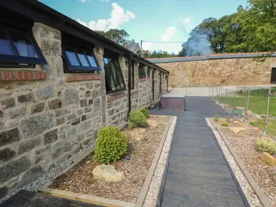 a brick building with a walkway next to a building at Nana's Cottage in Camborne