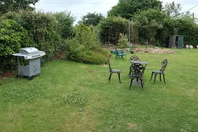 three chairs and a table in a yard with a grill at Kimberley Lane Static, Cornwall in Gwennap