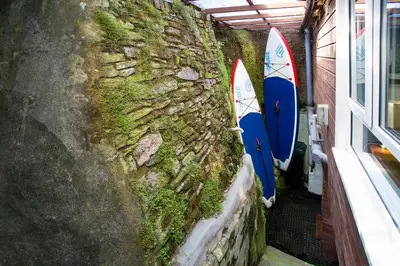 two surfboards are propped up against a stone wall at The Old Bakery in Falmouth