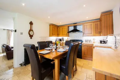 a kitchen with a wooden table and black chairs at The Old Bakery in Falmouth