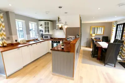 a kitchen with white cabinets and a dining table at 20 Tudor Court 