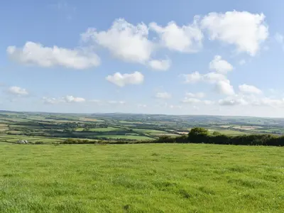 a field of green grass with a blue sky and clouds at The Owl's Roost - Uk12087 in Saint Endellion