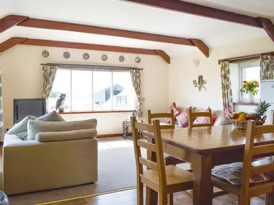 a living room with a wooden table and a couch at The Owl's Roost - Uk12087 in Saint Endellion