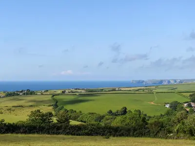 a green field with the ocean in the background at Stable Cottage - Uk12088 in Saint Endellion