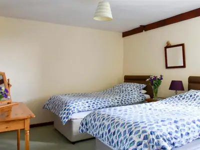 two beds in a bedroom with blue and white sheets at Stable Cottage - Uk12088 in Saint Endellion