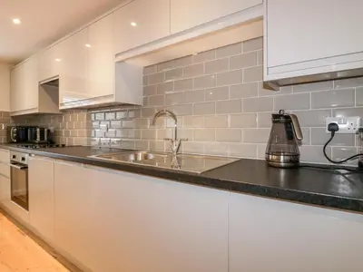 a kitchen with white cabinets and a sink at Midships in St Austell