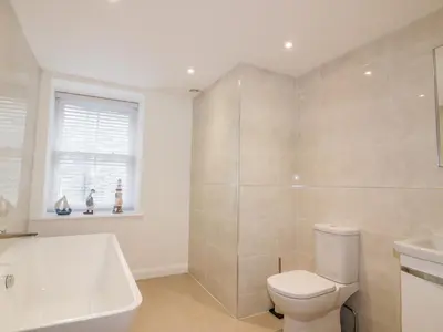 a bathroom with a toilet and a tub and a sink at Midships in St Austell