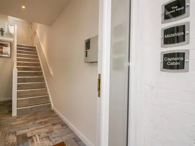 a hallway with stairs and a white door with signs on it at Midships in St Austell