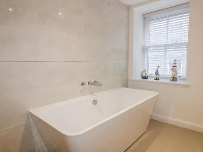 a white bath tub in a bathroom with a window at Midships in St Austell