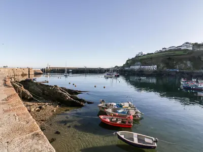 three boats are docked in the water next to a beach at The Crows Nest in St Austell