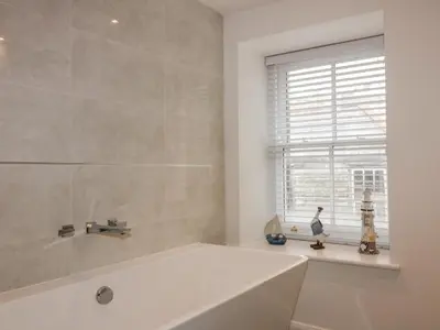 a white bathroom with a tub and a window at The Crows Nest in St Austell