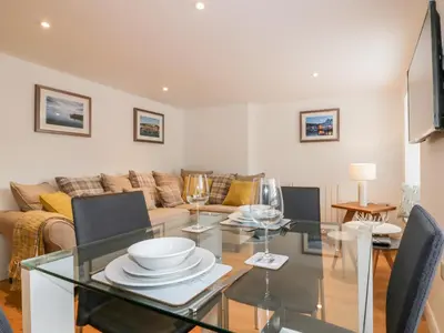 a living room with a glass table and chairs at The Crows Nest in St Austell