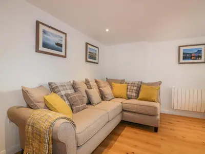 a living room with a couch with yellow pillows at The Crows Nest in St Austell