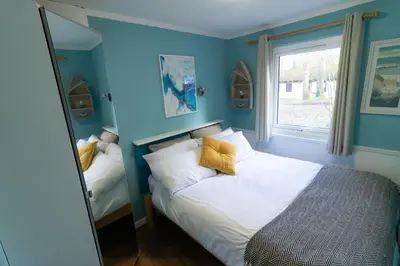 a bedroom with blue walls and a bed with yellow pillows at Ocean Cottage in Uny Lelant