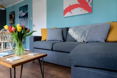 a living room with a couch and a table with flowers at Ocean Cottage in Uny Lelant