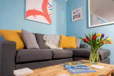 a living room with a couch and a vase of flowers on a table at Ocean Cottage in Uny Lelant
