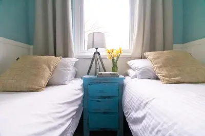a bedroom with two beds and a table with a lamp on it at Ocean Cottage in Uny Lelant