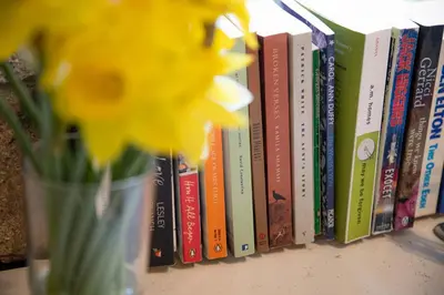 a vase with a yellow flower next to books at Ocean Cottage in Uny Lelant