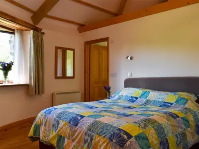 a bedroom with a bed with a colorful quilt at Round House - Uk12083 in Saint Endellion