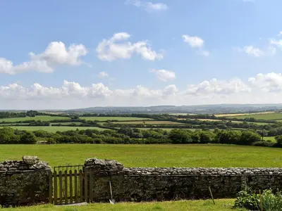 a stone fence in front of a green field at Round House - Uk12083 in Saint Endellion